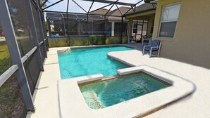 Una piscina con un jacuzzi, rodeada por un porche techado.