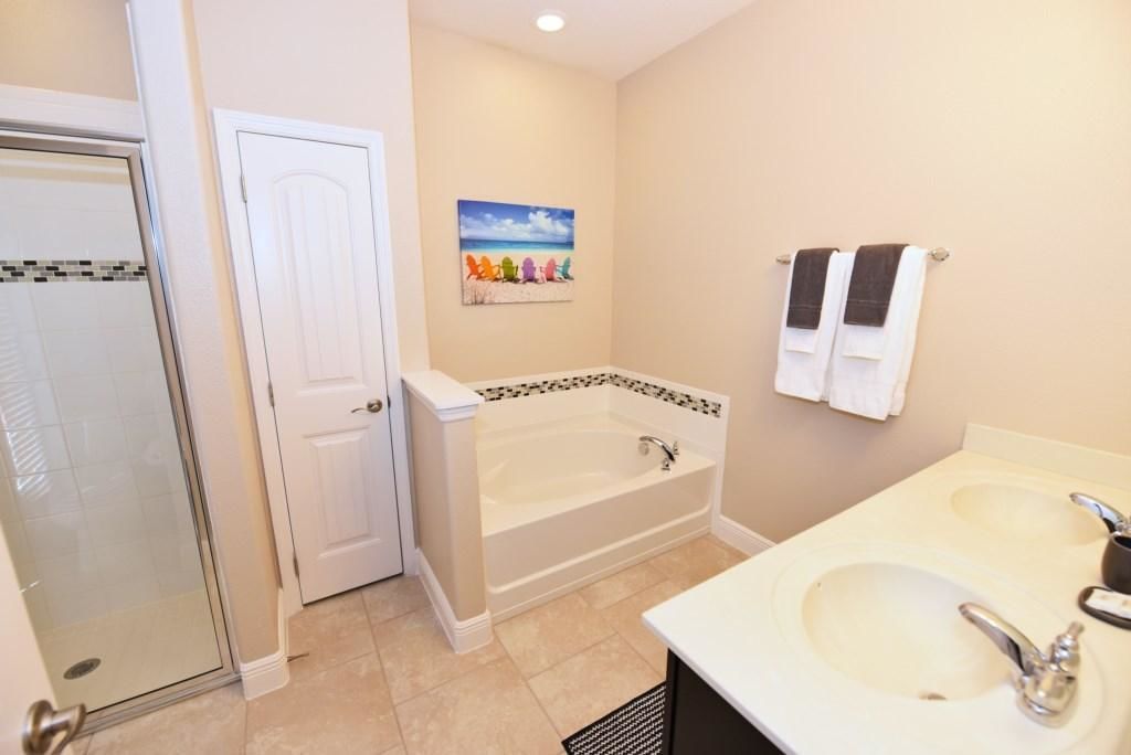 A bathroom with a glass shower enclosure, a bathtub, and two sinks.