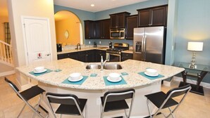 A modern kitchen with granite countertops, stainless steel appliances, and a central island with bar stools.