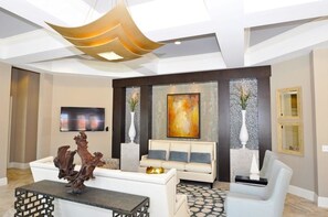 Relax in style with a modern living space featuring a statement wall art, comfortable sofa, and sleek light fixture.