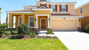 A two-story house with a garage, a front porch, and a well-maintained lawn.