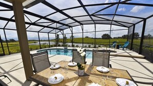 A covered outdoor dining area with a pool view, tables set with white tableware, and chairs. - 5336 Solterra House 5 Bedroom by Florida Star (Davenport)