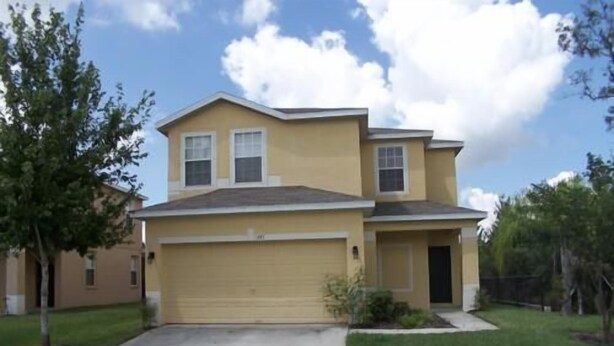 A two-story residential house with a garage, a front yard, and a driveway. - 541 Sandy Ridge House 4 Bedroom by Florida Star (Davenport)