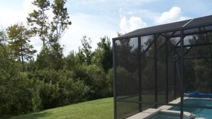A swimming pool with a glass enclosure. - 541 Sandy Ridge House 4 Bedroom by Florida Star (Davenport)