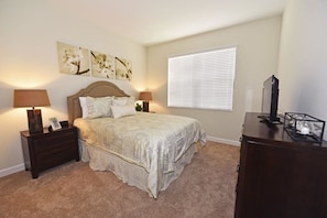 A bedroom with a bed, two bedside tables, a dresser, and a window with blinds. - 5439 Solterra House 5 Bedroom by Florida Star (Davenport)