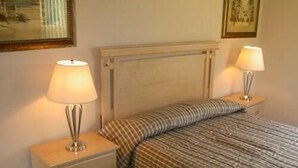 Ein Schlafzimmer mit einem Bett, zwei Nachttischen und Lampen.