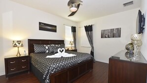 A bedroom with a bed, nightstands, a dresser, and a ceiling fan.