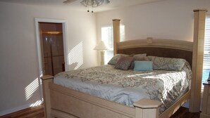 Une chambre à coucher avec un lit en bois, une table de chevet, une lampe et une fenêtre avec des stores.