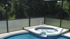 A hot tub with a tiled edge and a clear view of the surrounding greenery.