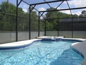Ein Pool mit gebogener Form, umgeben von einer Metallkonstruktion, mit Blick auf Bäume im Hintergrund.