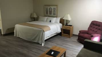 Een hotelkamer met een bed, nachtkastjes, een stoel en een kleintje tafeltje.