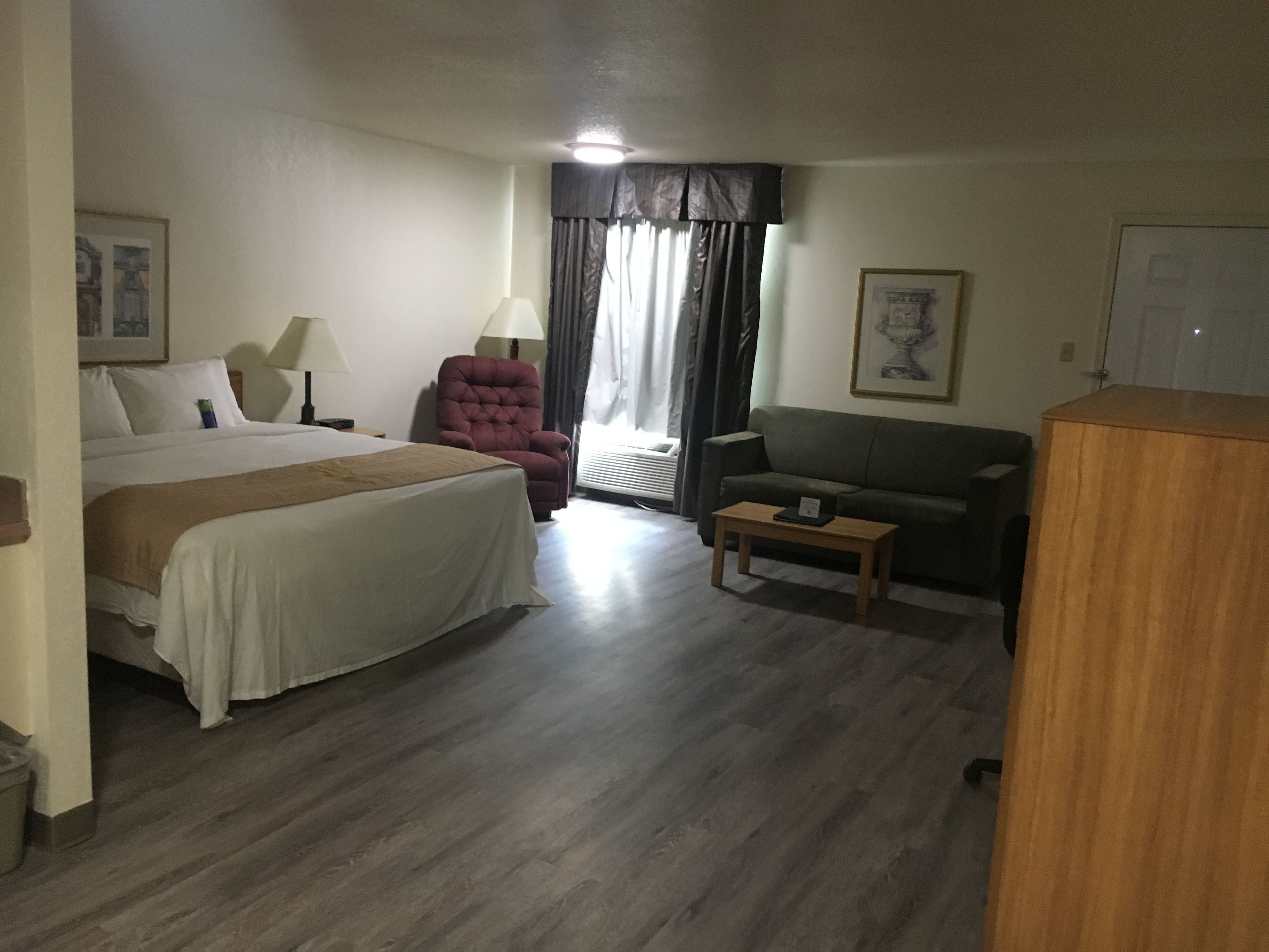 Ein Hotelzimmer mit einem Bett, einem Sofa, einem kleinen Tisch, einem Sessel und einem Schrank.
