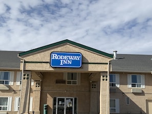 A Rodeway Inn building facade with a prominent sign, large windows, and a green roof. - Rodeway Inn (Edson)