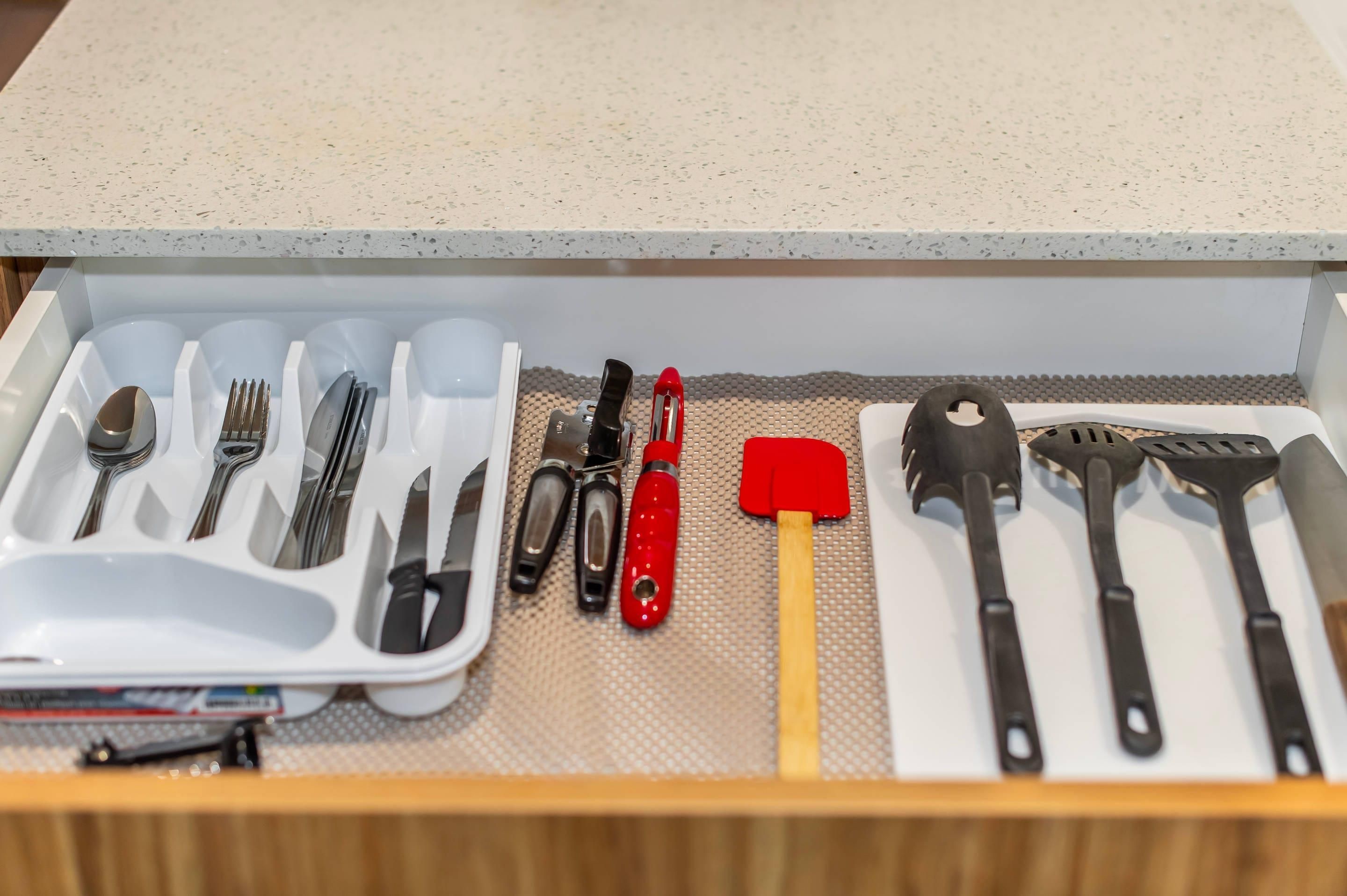 Un cajón con cubiertos y utensilios de cocina organizados en compartimentos.