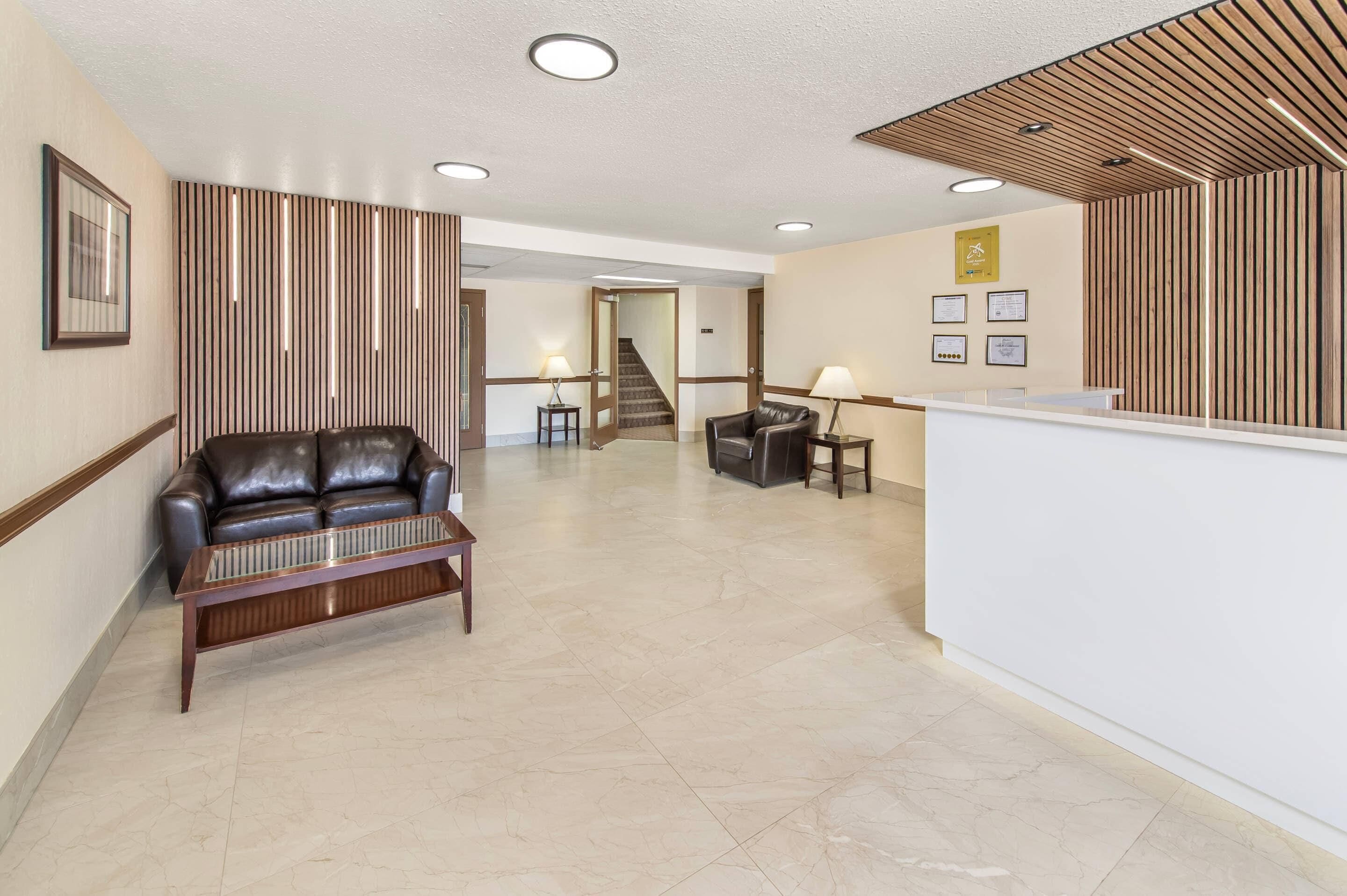 A hotel lobby with a leather sofa, a reception desk, and a staircase.