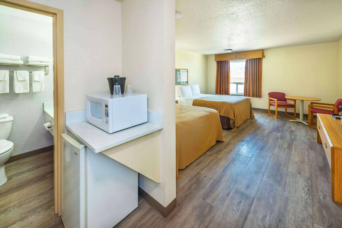Habitación de hotel con kitchenette, dos camas, un escritorio y una silla.