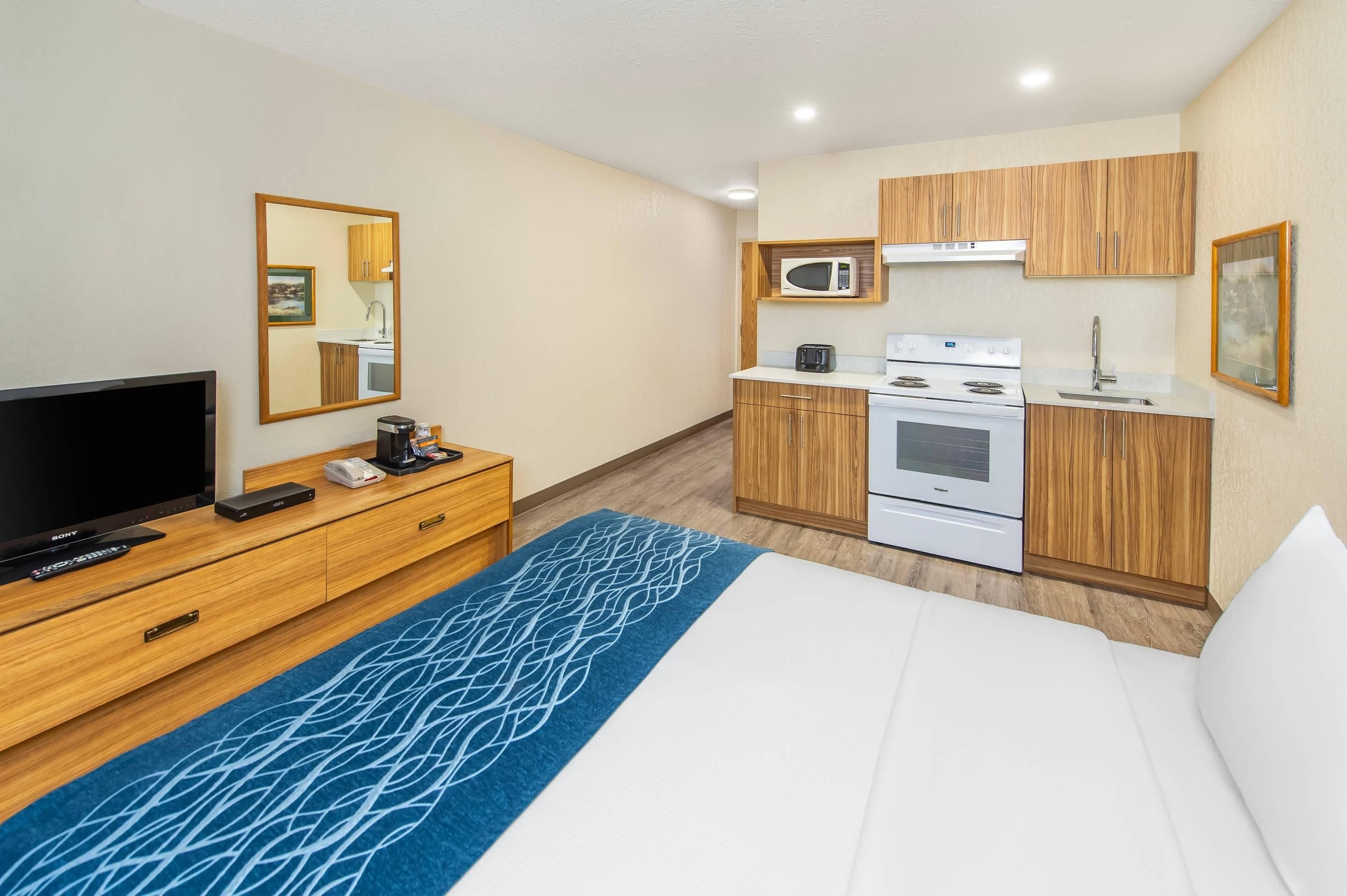 A hotel room with a bed, a TV, a coffee maker, a microwave, and a stove.