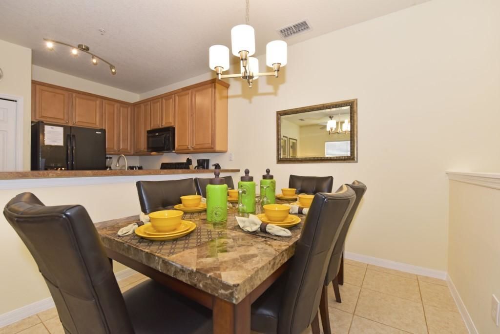 A dining area with a marble table, yellow plates, and green water bottles.
