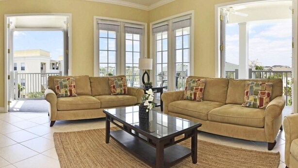 A living room with two beige sofas, a dark wooden coffee table, and a view of a balcony with a railing.