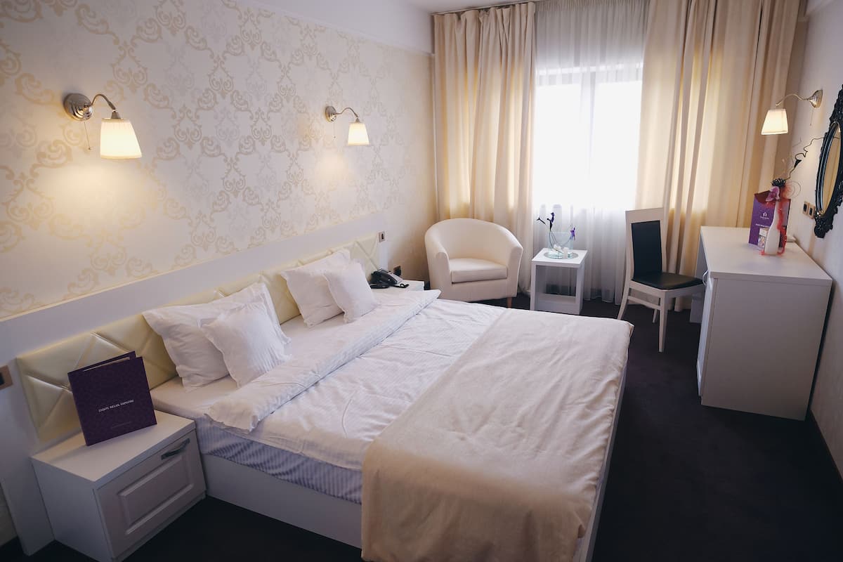 Ein Hotelzimmer mit Bett, Stuhl, Schreibtisch und Nachttisch.