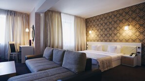 A hotel room with a bed, a sofa, a desk, and a nightstand. - Black Tulip (Dej)