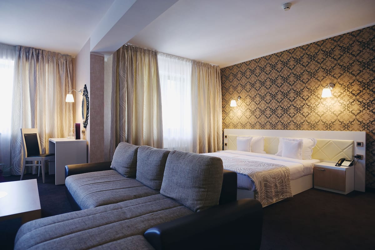 Ein Hotelzimmer mit Bett, Sofa, Schreibtisch und Nachttisch.