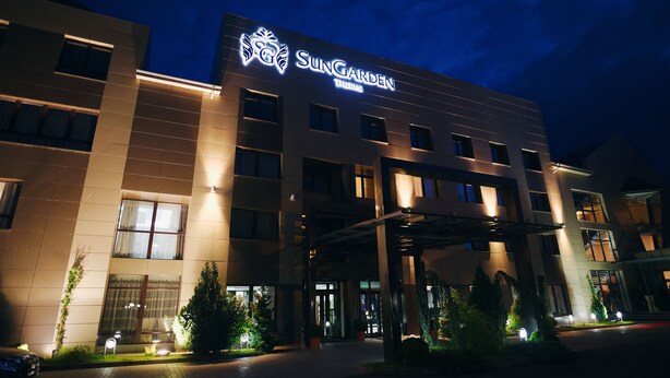 A hotel with a modern facade, illuminated signage, and a well-lit entrance area with potted plants. - Black Tulip (Dej)