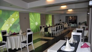 A dining area with tables set for a meal, featuring white tablecloths and black napkins. - Black Tulip (Dej)