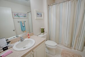 A bathroom with a white sink, a toilet, a bathtub, and a shower curtain.