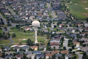 An aerial view of a residential area with houses, roads, and a golf course.