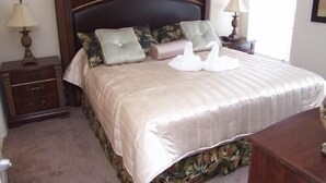 Una cama bien hecha con un cabecero oscuro, dos almohadas y un cisne decorativo sobre la colcha.