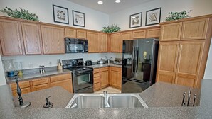 A kitchen with wooden cabinets, stainless steel appliances, granite countertops, and a double sink.