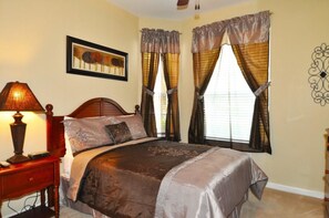 Un dormitorio con cama, mesita de noche, lámpara y cortinas.