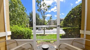 A balcony with two chairs, a table, and a bowl.