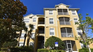A multi-story building with a beige facade, balconies, and a clear sky.