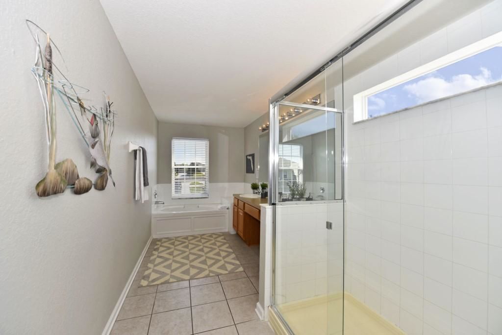 A modern bathroom with a glass shower enclosure, a bathtub, and a patterned rug.