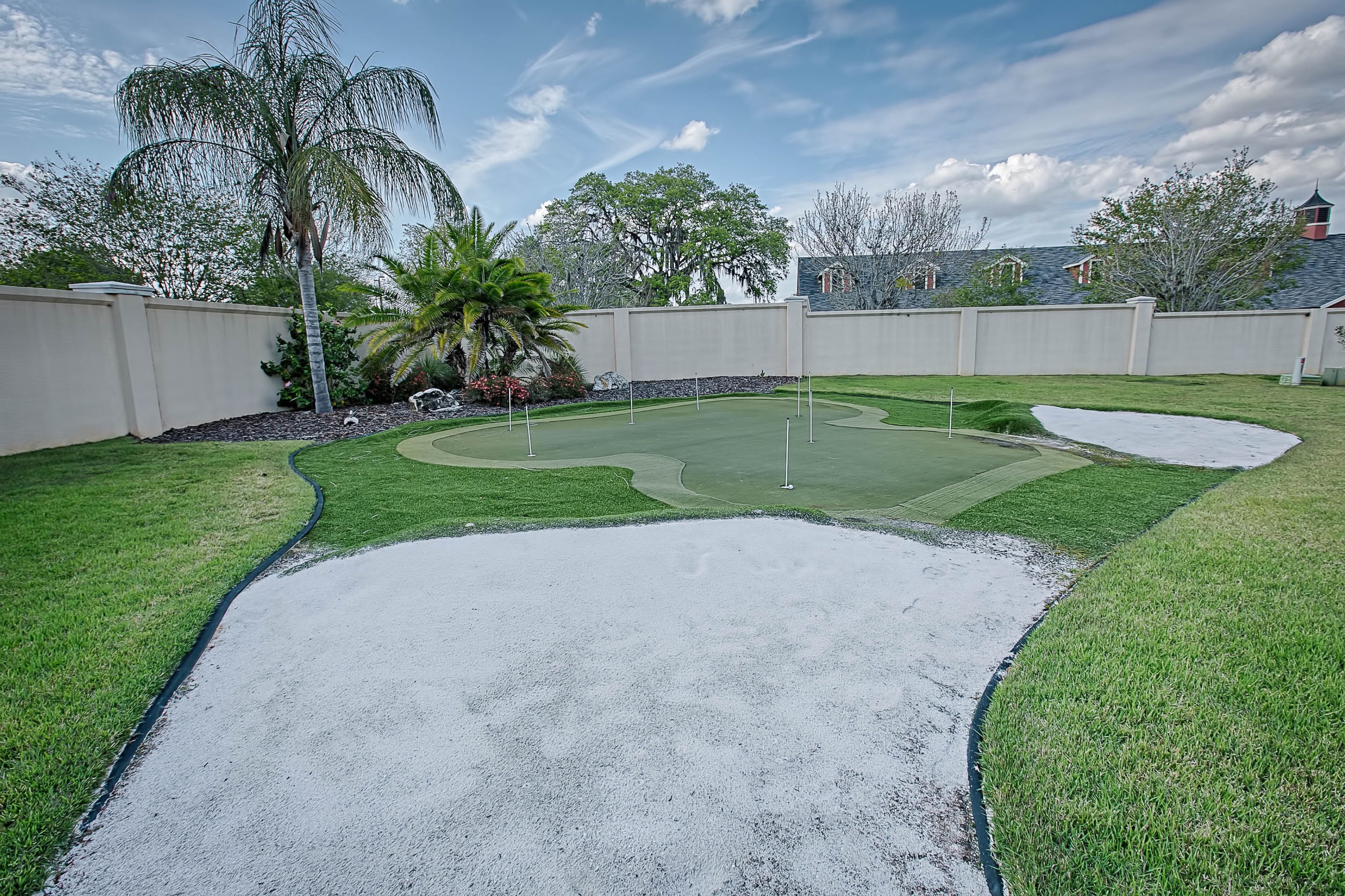 Um quintal com campo de golfe, bunkers de areia e uma palmeira.