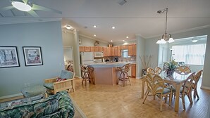 Une cuisine spacieuse avec des meubles en bois, un îlot central doté de tabourets et un coin repas avec une table et des chaises.