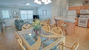 Un vaste salon comprenant un coin repas, une cuisine et un ventilateur de plafond.