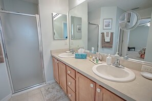Une salle de bain avec deux lavabos, un grand miroir et une douche.