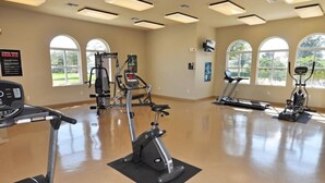 Un centre de remise en forme équipé d’appareils de cardio, notamment des tapis de course et un vélo elliptique, et doté de grandes fenêtres offrant une vue sur la verdure.