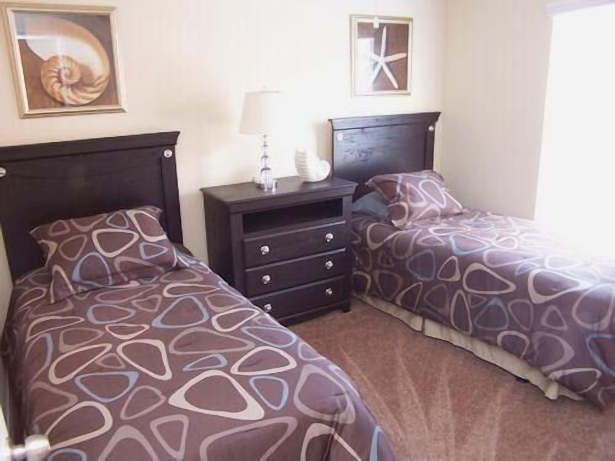 A bedroom with two beds, a dresser, and a nightstand.