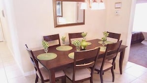 A dining table with six chairs, a mirror above it, and a chandelier.