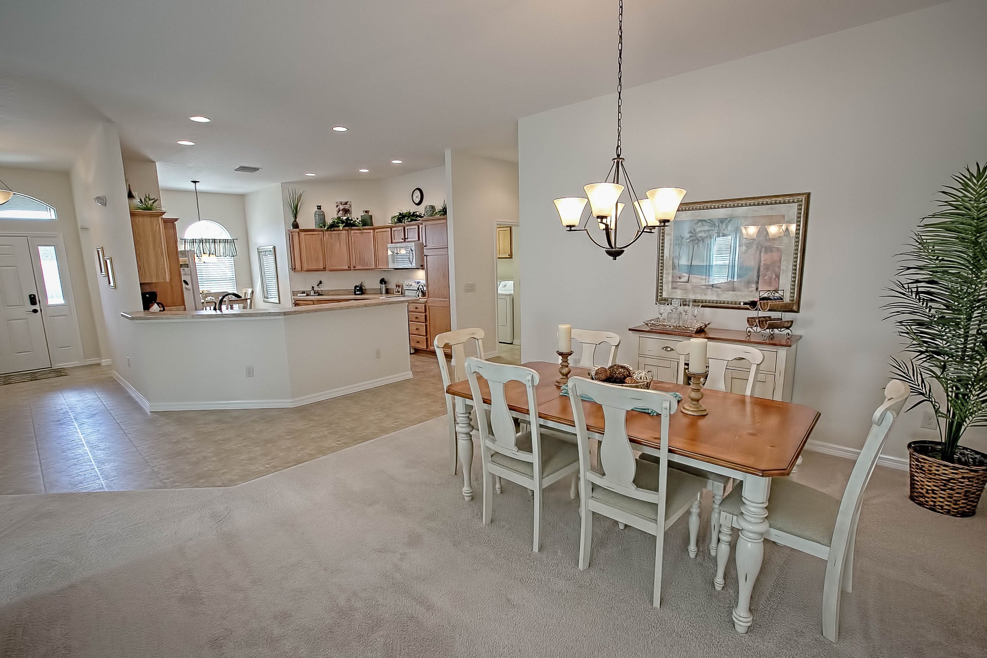 Una cocina amplia con armarios de madera, una isla central y un comedor con candelabro.