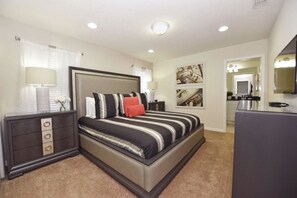 A bedroom with a large bed, a dresser, a mirror, and artwork on the walls. - 8878 Windsor Hills House 8 Bedroom by Florida Star (Kissimmee)