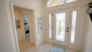 Un couloir avec un tapis à motifs, une porte à panneaux de verre et un tableau encadré accroché au mur.