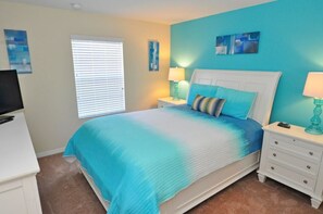 A bedroom with a bed, nightstands, a TV, and artwork on the walls. - 8939 Paraside Palms Townhome 4 Bedroom by Florida Star (Kissimmee)