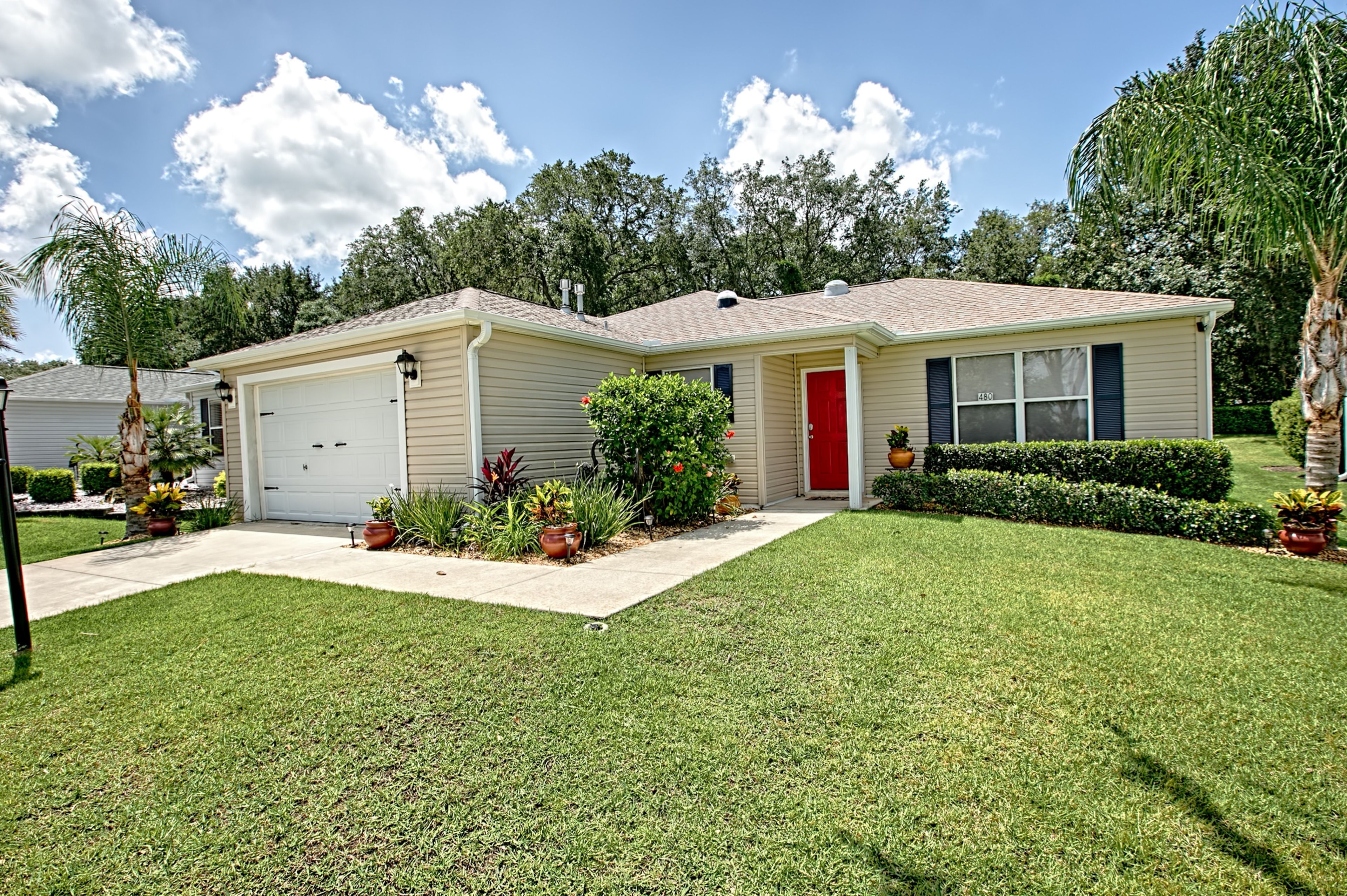 A single-story house with a red door, beige siding, and a front garage.