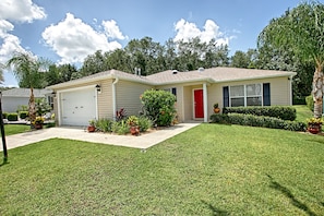 A single-story house with a red door, beige siding, and a front garage.