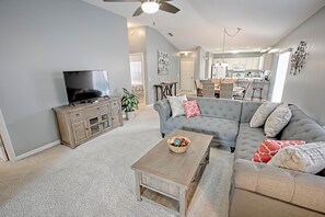 A spacious living room with a grey sofa, a wooden coffee table, and a TV on a wooden cabinet. - Nuevo Leon Lane Home 2 Bedroom by The VIR Group (Lady Lake)